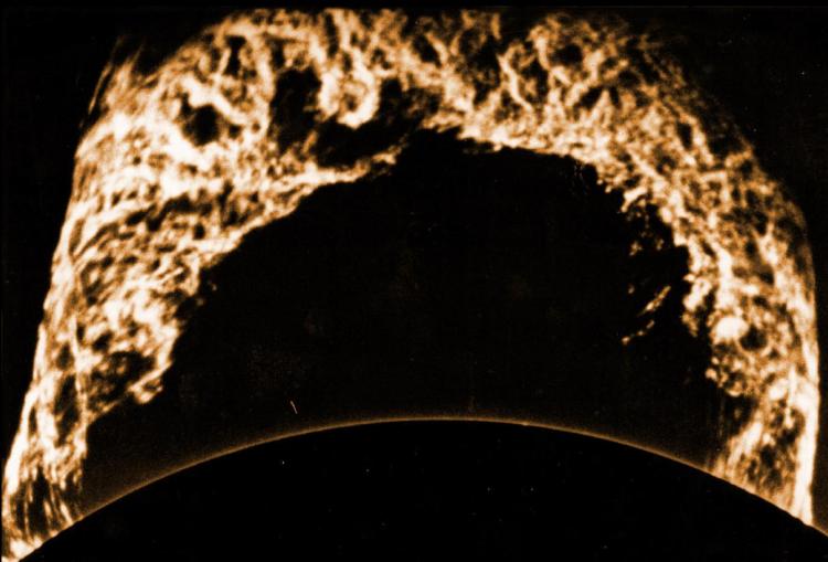 Some filaments and prominences can reach impressive sizes, and remain visible very far above the solar disk. This prominence was photographed in June 1946 again through a filter centered on H-alpha, and extends some 200000 km above the solar surface; the Earth would easily fit under it. The bright arch at the bottom of the picture delineates the solar limb. Prominences extending so far up above the photosphere are usually not static, but are expanding outward in an eruptive phase.