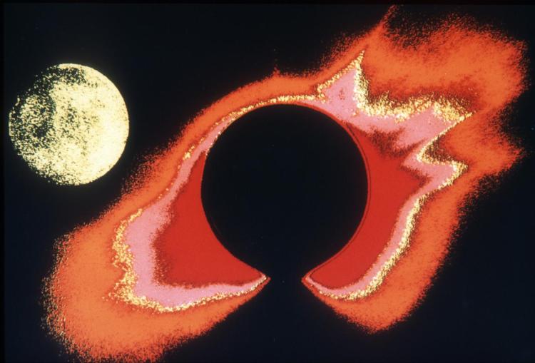 This false-color image of the solar corona was made with the white-light coronagraph aboard the Skylab spacecraft, with the moon (upper left) approaching the sun to create the total eclipse of 30 June 1973. Here, the light from the solar disk is blocked by an occulting disk, which appears as the solid black circle in the center of the field. The black gap at the bottom is the shadow of a pylon, which holds the occulting disk in place. The colors were added to the image by computer processing after the data were analyzed.