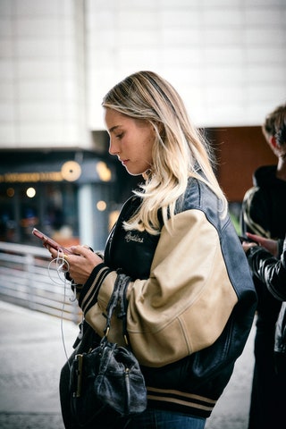 Image may contain Clothing Coat Jacket Blonde Hair Person Accessories Bag Handbag Adult Face Head Smoke and Gun